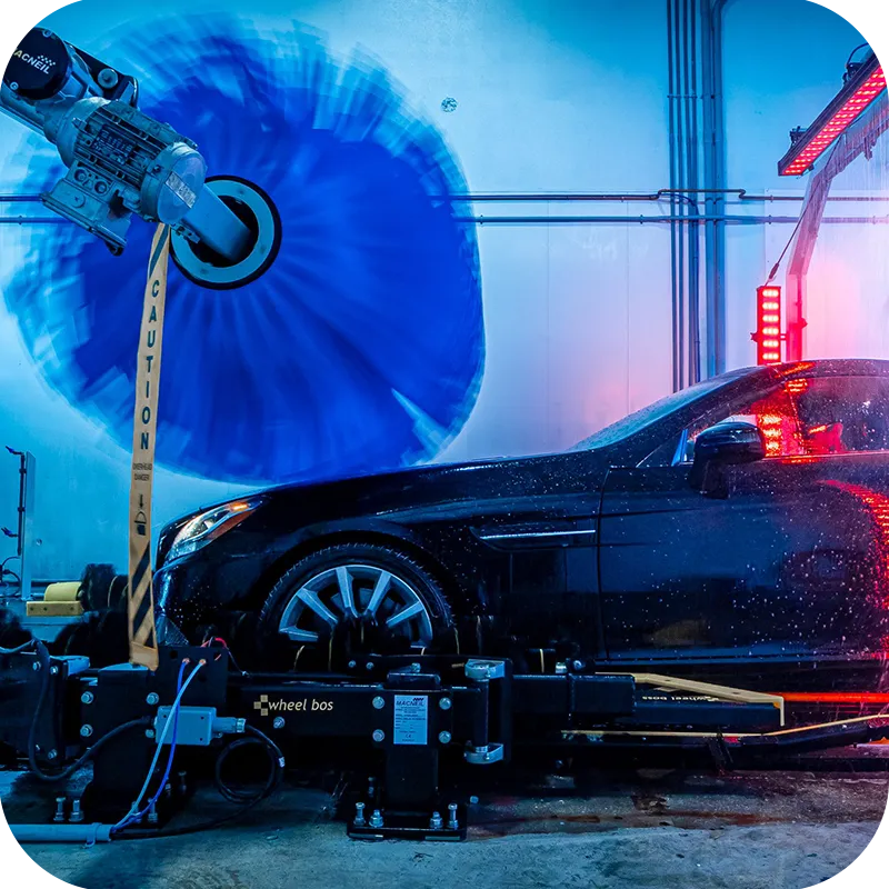 Car moving through AquaShine Express car wash tunnel with large blue rotating brush and water spraying for a deep clean